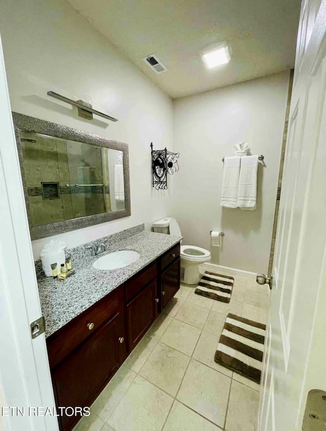 bathroom with toilet, vanity, tile patterned floors, and a shower with door