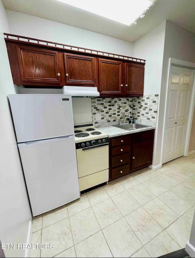 kitchen featuring tasteful backsplash, sink, light tile patterned floors, and white appliances