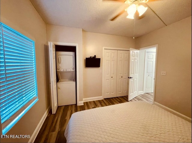 unfurnished bedroom featuring ceiling fan, a closet, dark wood-type flooring, and stacked washer and clothes dryer