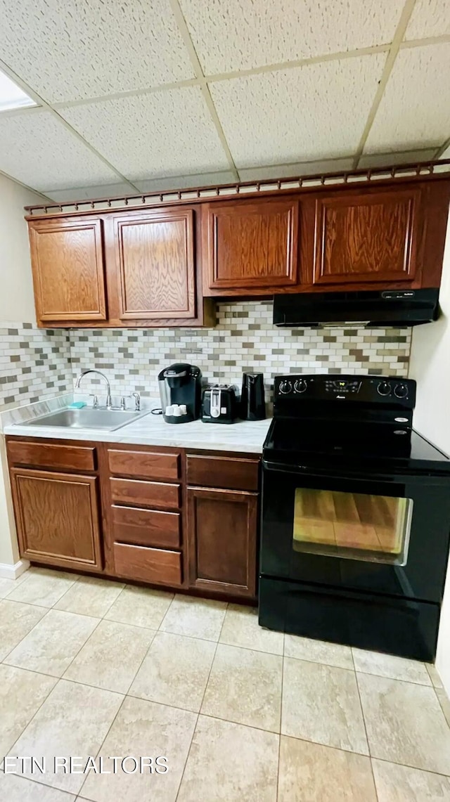 kitchen featuring black range with electric stovetop, sink, backsplash, a paneled ceiling, and light tile patterned floors