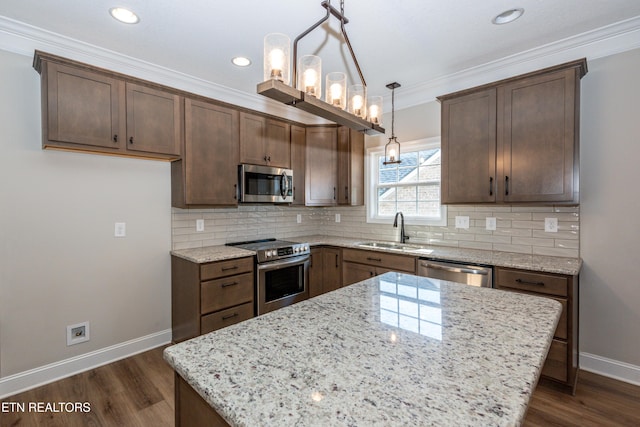 kitchen featuring appliances with stainless steel finishes, decorative backsplash, a sink, and ornamental molding