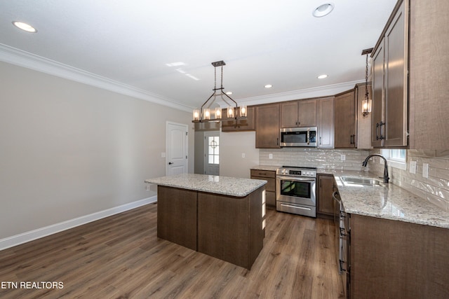 kitchen with dark wood-style floors, stainless steel appliances, backsplash, a sink, and baseboards