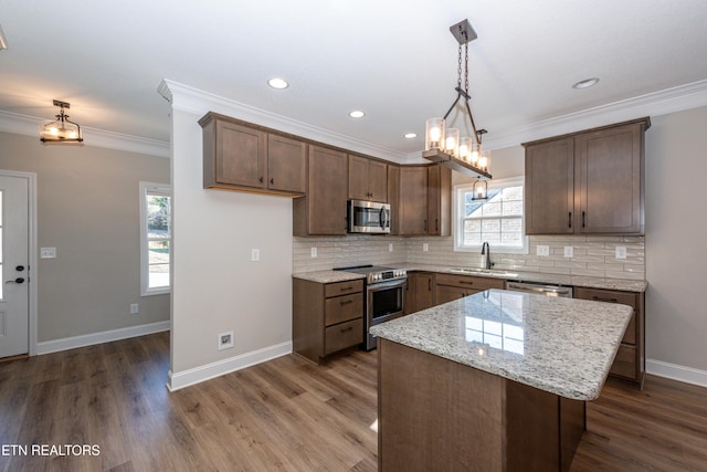 kitchen with stainless steel appliances, a sink, ornamental molding, and tasteful backsplash