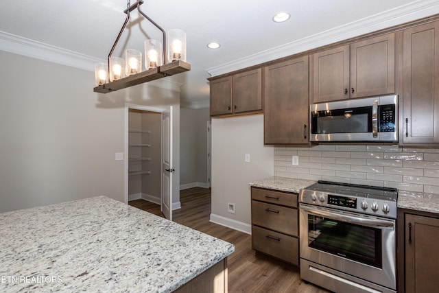 kitchen with light stone counters, appliances with stainless steel finishes, dark wood-style flooring, ornamental molding, and backsplash