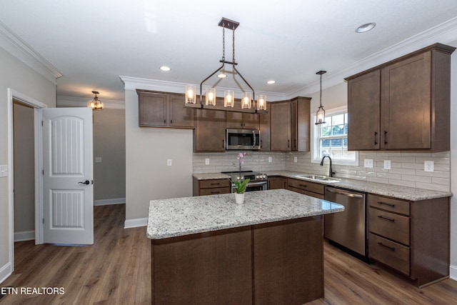 kitchen featuring dark wood-type flooring, a sink, ornamental molding, appliances with stainless steel finishes, and decorative backsplash