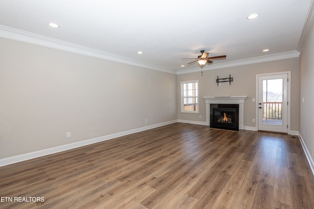 unfurnished living room featuring wood finished floors, ornamental molding, a glass covered fireplace, and a healthy amount of sunlight