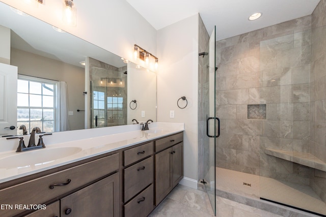 full bathroom with a stall shower, a sink, baseboards, and double vanity