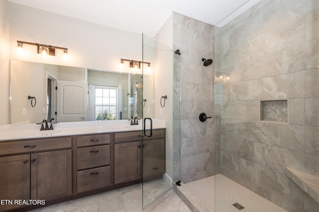 bathroom with a sink, a tile shower, and double vanity