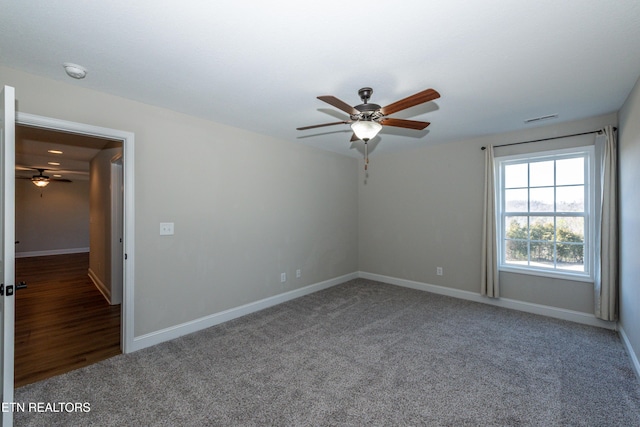 carpeted spare room with baseboards, visible vents, and a ceiling fan