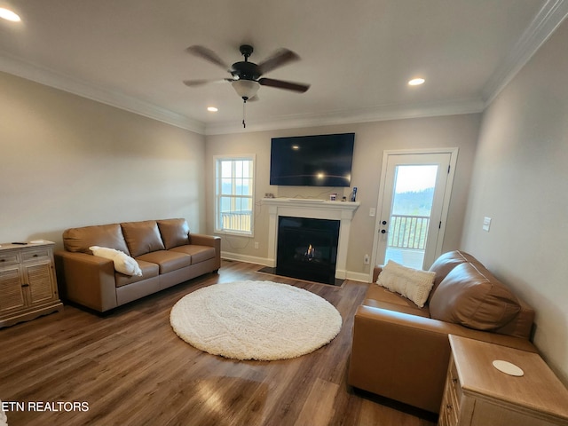 living area with a wealth of natural light, crown molding, and wood finished floors