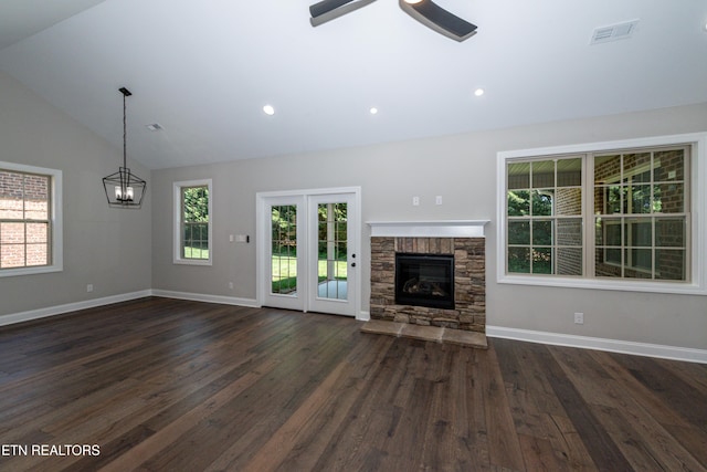 unfurnished living room with ceiling fan with notable chandelier, a fireplace, dark wood-type flooring, lofted ceiling, and baseboards