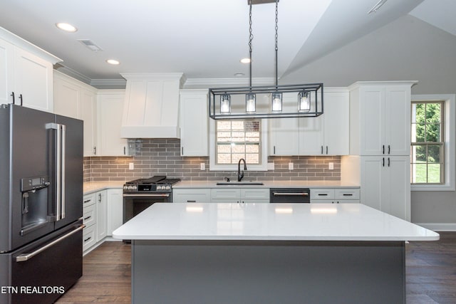 kitchen with dishwashing machine, stainless steel gas range, a sink, custom range hood, and high end black fridge