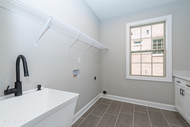 laundry area with laundry area, electric dryer hookup, washer hookup, a sink, and baseboards