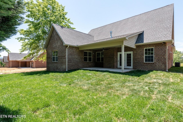 rear view of property featuring a patio area, brick siding, a lawn, and roof with shingles