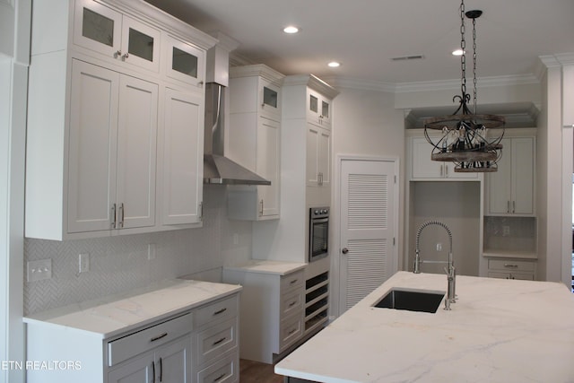 kitchen with wall oven, white cabinets, sink, pendant lighting, and a center island with sink