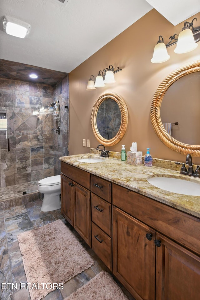 bathroom with vanity, toilet, and a tile shower