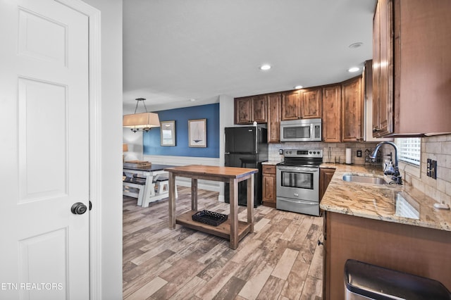 kitchen with tasteful backsplash, sink, decorative light fixtures, and appliances with stainless steel finishes