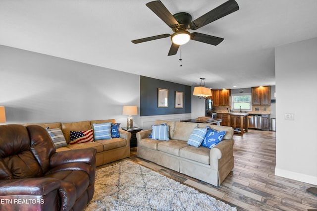 living room featuring sink, ceiling fan with notable chandelier, and hardwood / wood-style flooring