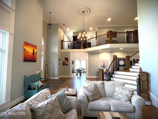 living room featuring a healthy amount of sunlight, a towering ceiling, hardwood / wood-style floors, and an inviting chandelier