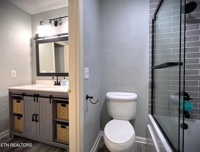 full bathroom with hardwood / wood-style flooring, vanity, toilet, and combined bath / shower with glass door