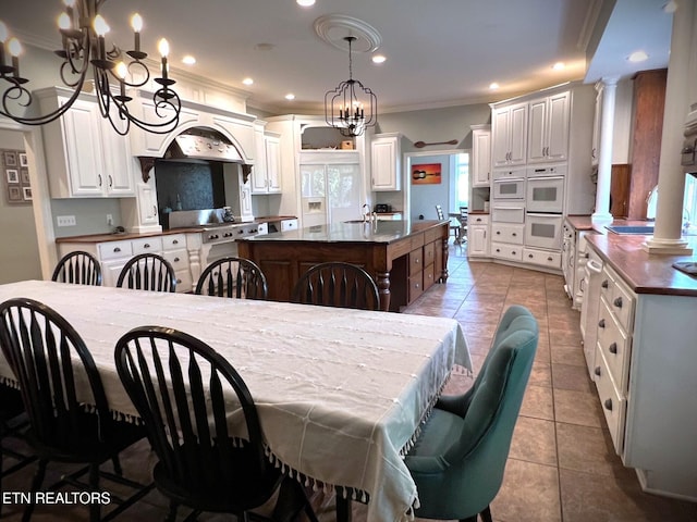 dining area with ornamental molding, tile patterned floors, sink, and decorative columns