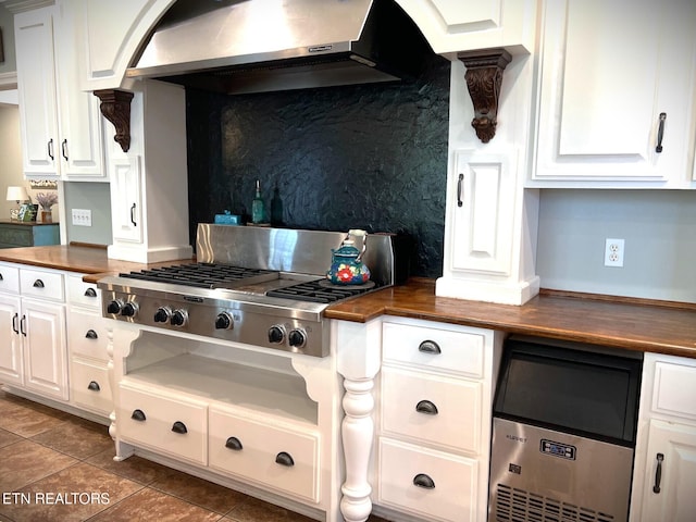 kitchen featuring white cabinetry, butcher block counters, dark tile patterned flooring, stainless steel gas cooktop, and exhaust hood