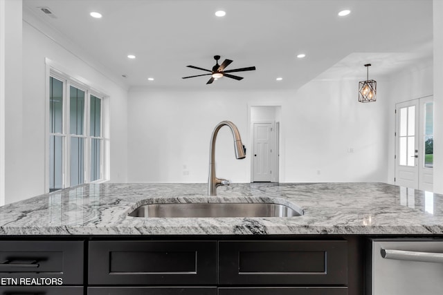 kitchen with ceiling fan, light stone counters, and sink