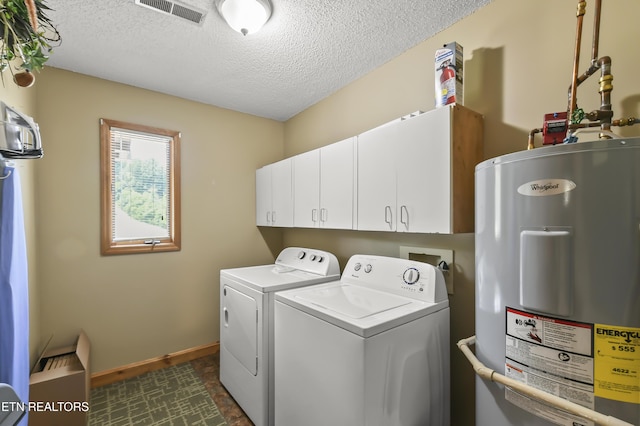 laundry room featuring washer and dryer, cabinets, water heater, and a textured ceiling