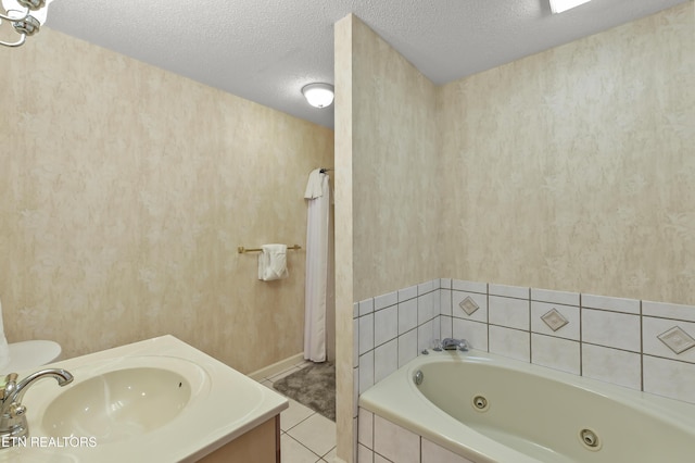 bathroom featuring tiled tub, vanity, tile patterned floors, and a textured ceiling