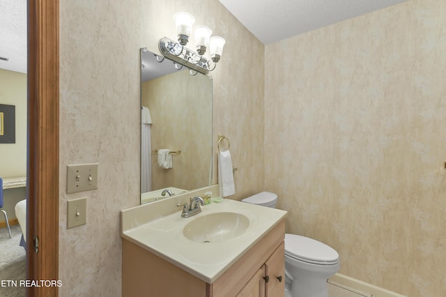 bathroom with vanity, toilet, and a textured ceiling