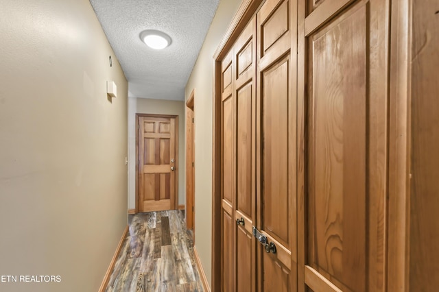 corridor with dark hardwood / wood-style floors and a textured ceiling