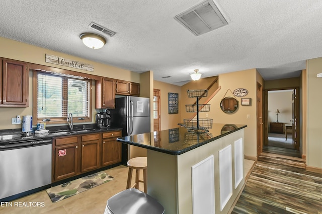 kitchen featuring sink, a kitchen island, stainless steel appliances, dark hardwood / wood-style floors, and a kitchen bar