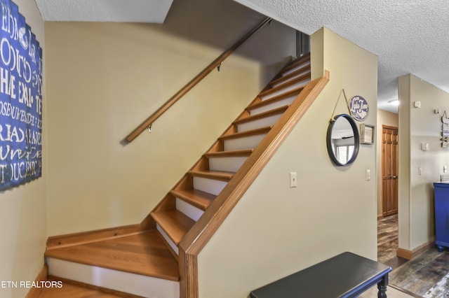 stairs with hardwood / wood-style flooring and a textured ceiling