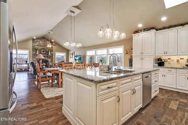 kitchen featuring tasteful backsplash, light stone counters, vaulted ceiling, dark wood-type flooring, and a center island with sink