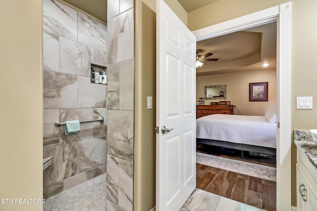 bathroom featuring ceiling fan, wood-type flooring, tiled shower, and vanity