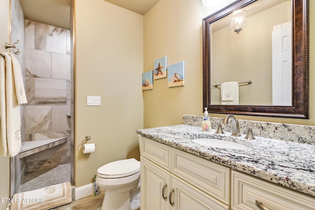 bathroom featuring vanity, toilet, and a tile shower