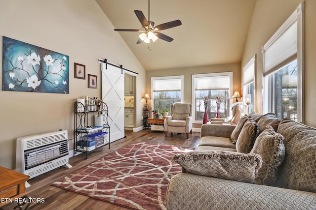 living room with dark hardwood / wood-style flooring, heating unit, ceiling fan, a barn door, and high vaulted ceiling