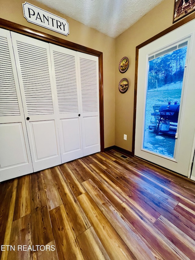 unfurnished bedroom featuring a textured ceiling, hardwood / wood-style flooring, and a closet