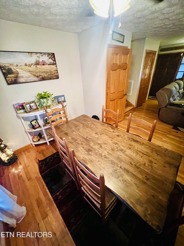 dining room with hardwood / wood-style flooring and a textured ceiling