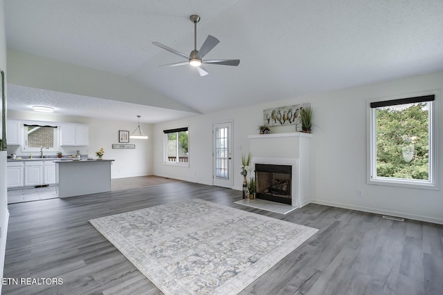 unfurnished living room featuring sink, vaulted ceiling, ceiling fan, and a healthy amount of sunlight