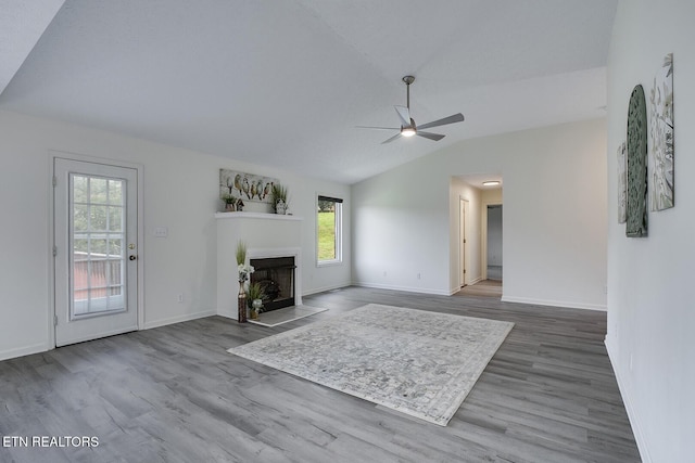 unfurnished living room featuring ceiling fan, a wealth of natural light, hardwood / wood-style floors, and lofted ceiling