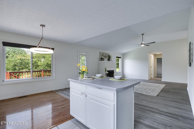 kitchen featuring a center island, ceiling fan, pendant lighting, white cabinets, and lofted ceiling