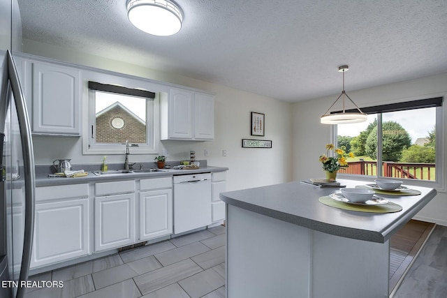 kitchen featuring stainless steel refrigerator, white cabinets, dishwasher, and sink