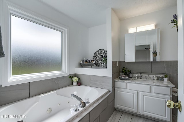 bathroom featuring a relaxing tiled tub and vanity