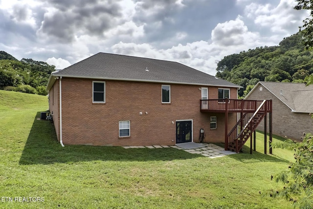 rear view of house with central air condition unit, a deck, and a lawn