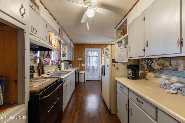 kitchen with black appliances, ceiling fan, wooden walls, white cabinets, and sink