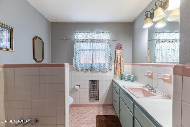 bathroom with toilet, tile walls, tile patterned floors, heating unit, and vanity