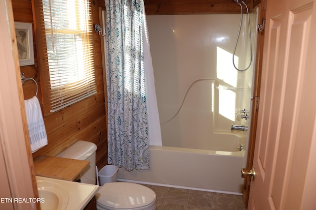 full bathroom with wooden walls, tile patterned flooring, toilet, shower / bath combo, and vanity