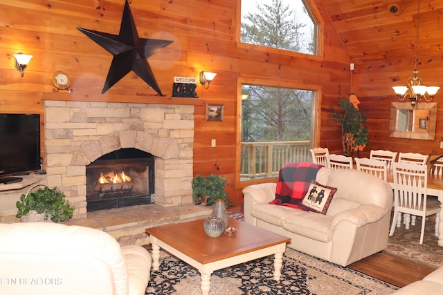 living room featuring a fireplace, lofted ceiling, wooden walls, and a chandelier