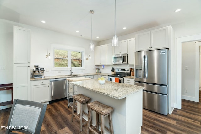 kitchen featuring appliances with stainless steel finishes, a center island, white cabinets, and decorative light fixtures